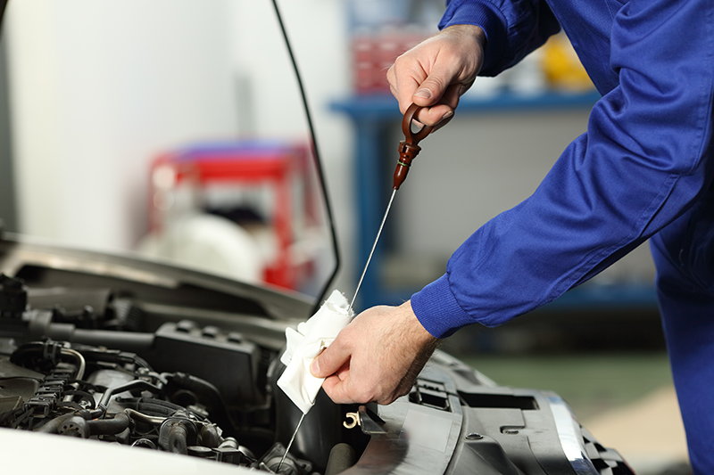 Mechanic checking car engine oil with a dipstick